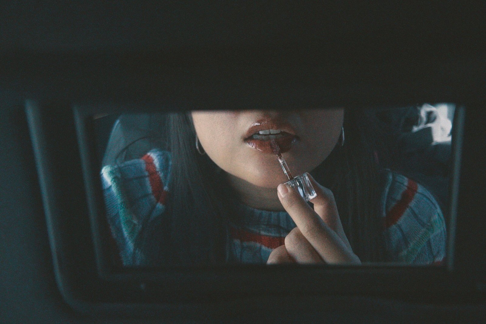 A girl putting lip gloss